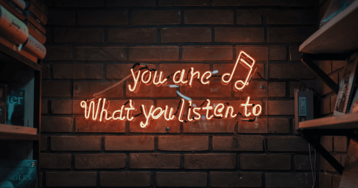 Neon sign against a brick wall. The sign reads "You are what you listen to".